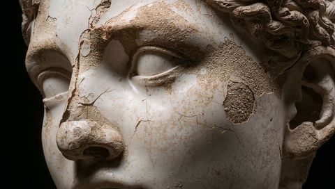 Marble sculpture head presenting weathered surface with cracks, flaking and patina details