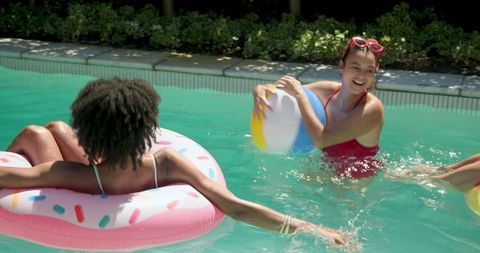 Young Women Relaxing and Enjoying Fun in Sun with Pool Floats and Beach Balls