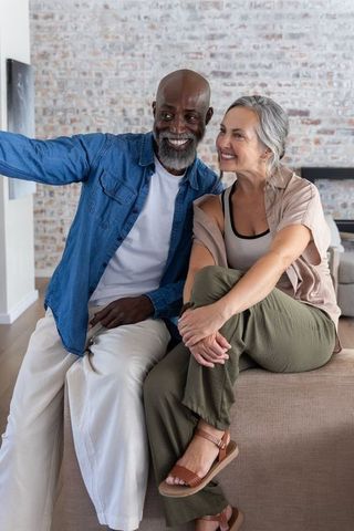 Smiling african american man and mature woman relaxing together on modern living room sofa