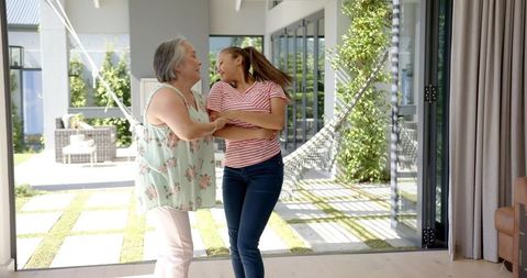 Grandmother and granddaughter dancing in sunlit room