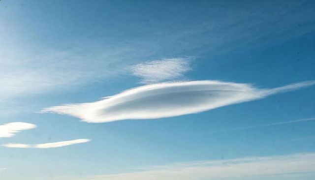 Lenticular cloud forming lens shape over clear blue sky minimalist high altitude vista
