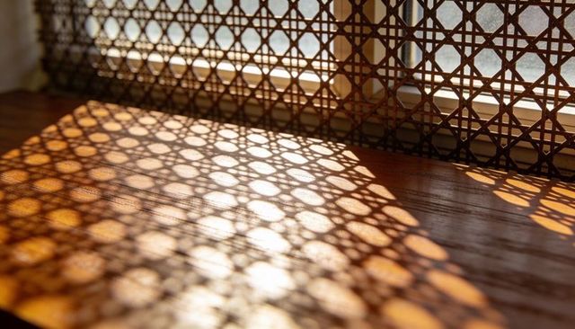 Casting geometric lattice shadows across wooden tabletop in warm sunlight