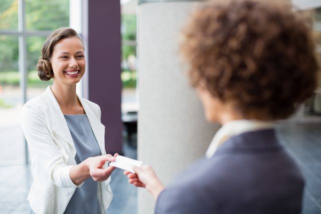 Business executives exchanging business cards at a conference, highlighting professional networking and corporate connections. Ideal for use in business-related articles, networking event promotions, corporate training materials, and professional development resources.