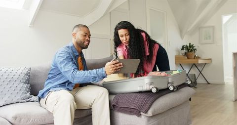 Couple Preparing for Vacation with Tablet and Luggage