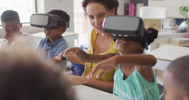 Young students in a classroom setting engage with virtual reality technology under the guidance of a teacher. They appear engrossed in a digital experience, indicating modern educational methods. This image is ideal for illustrating topics related to innovative teaching techniques, the integration of technology in education, and interactive learning environments.