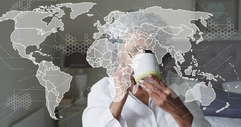 Sipping senior woman in white robe holding mug with global map and digital network overlay
