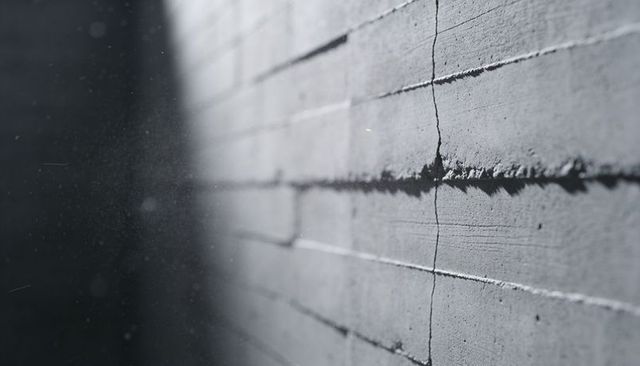 Gritty concrete wall panel running diagonally with seam and crack in industrial interior