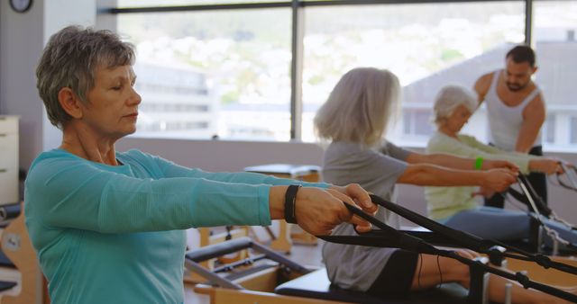 Senior women working out in fitness class on reformer machines for strength training - Download Free Stock Images Pikwizard.com