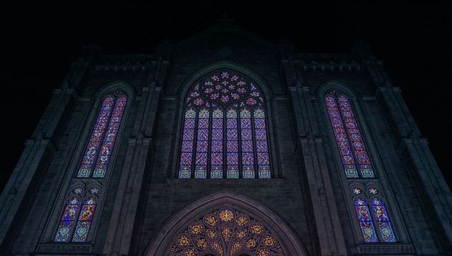 Illuminated gothic cathedral at night with stained glass windows