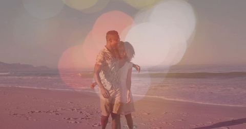 African american couple walking on sunset beach with romantic golden bokeh and lensflare