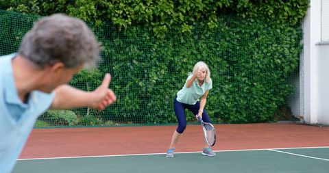 Senior Couple Enjoying Tennis Game with Thumbs Up
