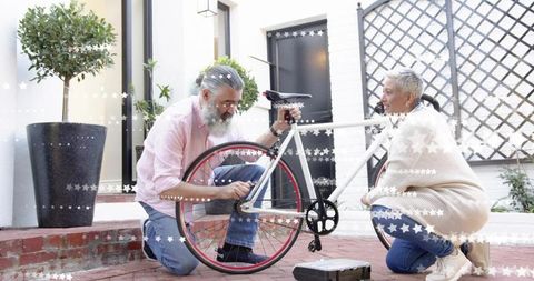 Senior couple repairing white bicycle on brick courtyard, teamwork and diy maintenance