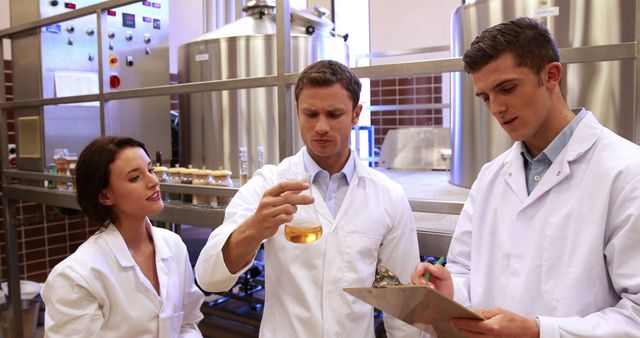 Three Caucasian chemistry professionals are examining a liquid in a lab setting. - Download Free Stock Photos Pikwizard.com