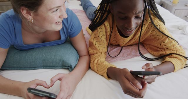 Two Friends Lying on Bed Using Smartphones Smiling - Download Free Stock Images Pikwizard.com