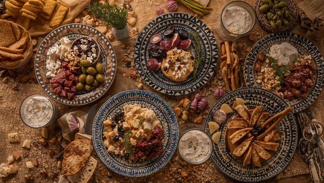 Mediterranean mezze spread showcasing patterned ceramics, olives, cheeses, rustic breads