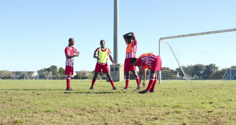 Young Soccer Players Stretching and Discussing Strategy on Sunny Field