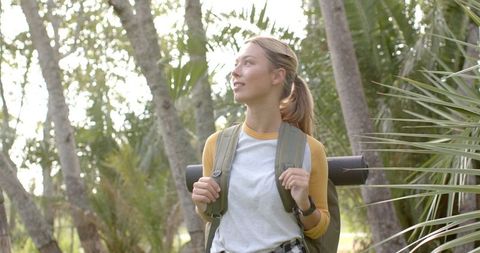 Young Woman Hiking Through Lush Park on Sunny Day