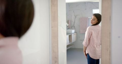 Woman Adjusting Shirt in Mirror During Morning Routine at Home