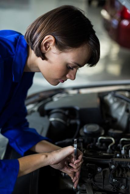 Female mechanic servicing a car in repair garage