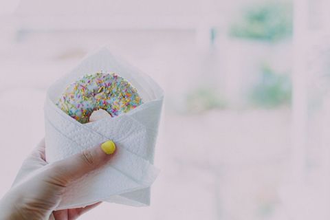 Hand Holding Delicious Sprinkle Donut Closeup