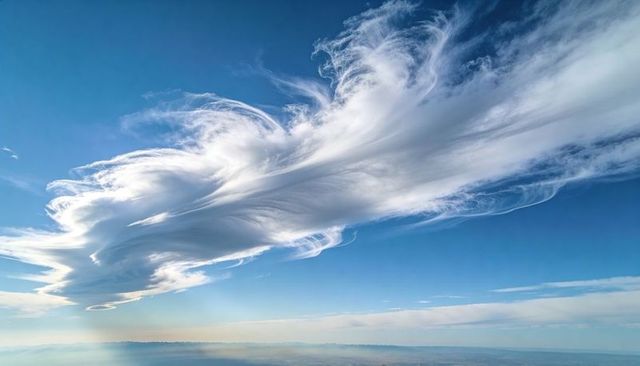 Majestic lenticular and cirrus cloud formation arching over hazy distant horizon