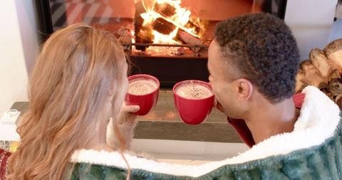 Couple Enjoying Warm Drinks by Cozy Fireplace