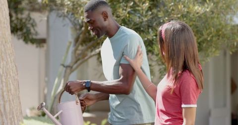 Couple Watering Tree in Garden with Pink Watering Can