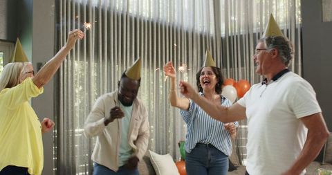 Diverse colleagues celebrating with sparklers at office party