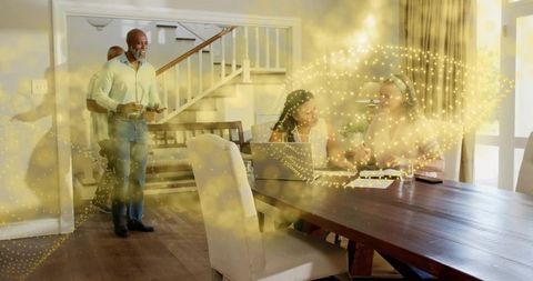 Multigenerational team collaborating at dining table with laptop and documents in warm golden light