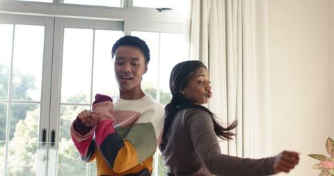 Diverse Female Friends Joyfully Dancing in Living Room