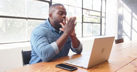 Focused Man Typing on Laptop with Smartphone Nearby in Modern Office