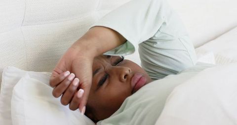 Mid-adult african american woman lying in bed wearing mint long-sleeve top closeup calm repose