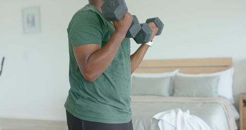 Adult African Man Doing Dumbbell Workout in Bedroom for Home Strength Training