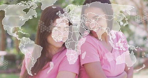 Women wearing pink ribbons back-to-back in park with world map overlay for global awareness
