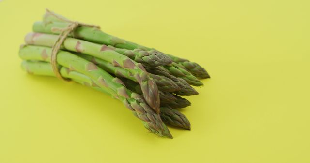 Image of close up of bundle of fresh asparagus over green background. fusion food, fresh vegetables and healthy eating concept.