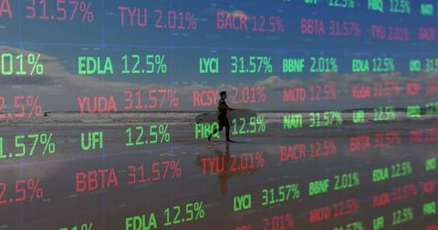 Surfer walking carrying surfboard on wet sand with stock market ticker overlay