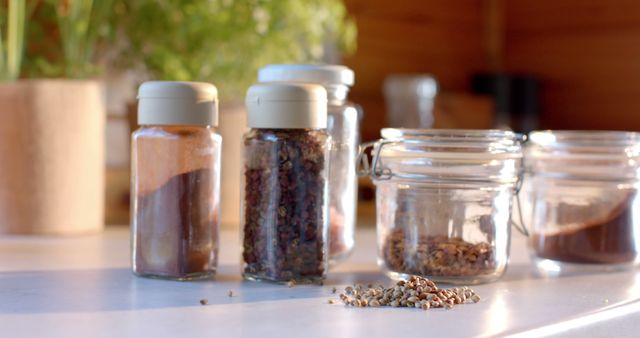 Various spices and herbs in glass jars on kitchen counter, blending scene with focus on culinary ingredients. Good for content on cooking, recipe blogs, healthy eating, kitchen organization tips.