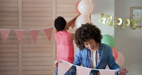 Women decorating room with balloons and banner for upcoming party