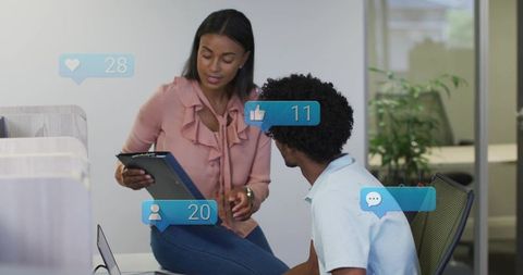 Coworkers collaborating over tablet with social media overlays in modern open office