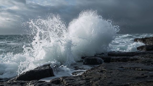 Storm wave crashing against basalt ledges with dramatic ocean spray and coastal foam