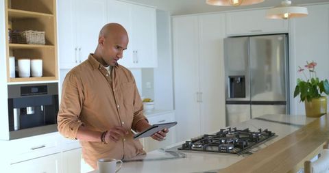 Mature African American man using tablet with stylus at modern kitchen island