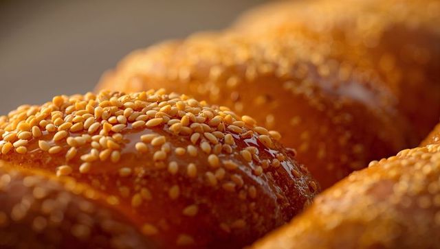 Glistening braided challah loaf topped with sesame seeds and glossy honey glaze