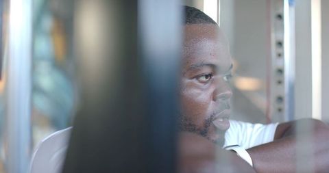 African man resting at gym between sets wearing white t-shirt and smartwatch