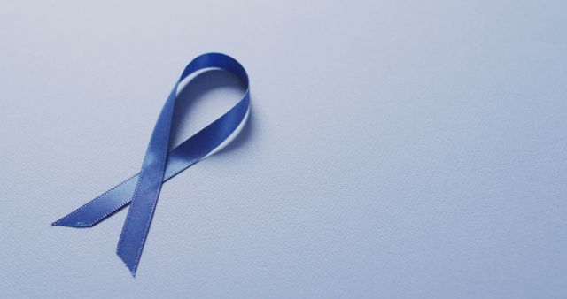 Image of dark blue colon cancer ribbon on pale blue background. medical and healthcare awareness support campaign symbol for colon cancer.