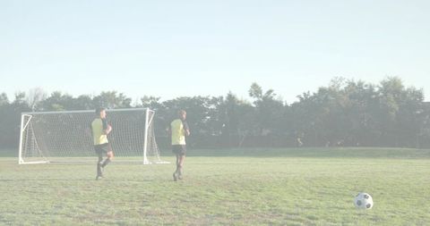 Young soccer players jogging near portable goal on sunny park field for training