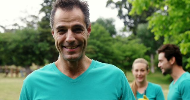 Smiling Volunteer in Green Shirt Standing Outdoors - Download Free Stock Images Pikwizard.com