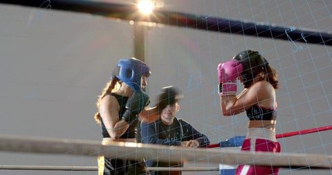 Female Boxers Sparring with Headgear and Gloves Under Coach Guidance in Intense Gym Training