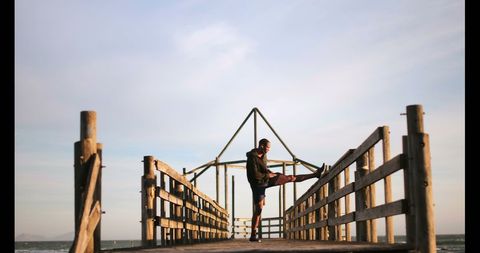 Young Man Jogger Stretching on Seaside Wooden Pier in Afternoon Sun - Download Free Stock Images Pikwizard.com