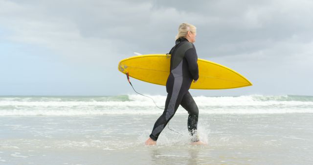Senior Woman Carrying Yellow Surfboard on Beach - Download Free Stock Images Pikwizard.com