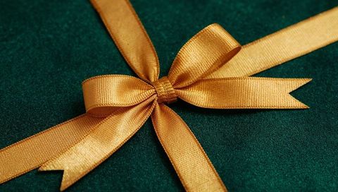 Shimmering golden satin bow resting on deep green velvet for luxury gift presentation